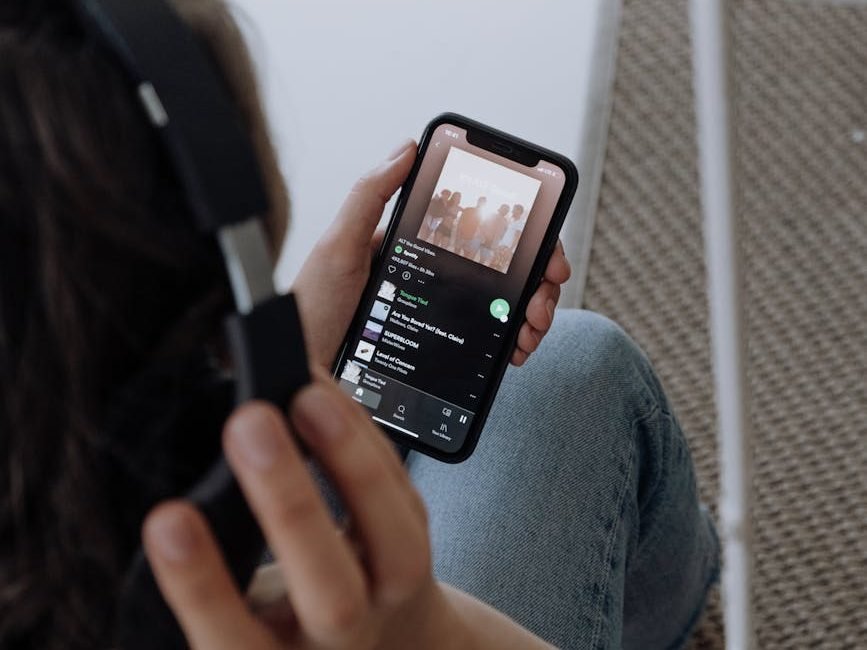 woman in gray sweater holding black smartphone